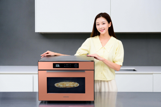 삼성전자 모델이 '비스포크 오븐'에 AI 비전 인식 기술을 기반으로 한 '카메라 식품 인식' 기능을 소개하고 있다. 삼성전자 제공